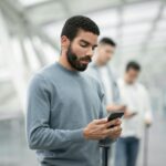 Middle Eastern Tourist Man Using Cellphone Texting In Airport Indoors