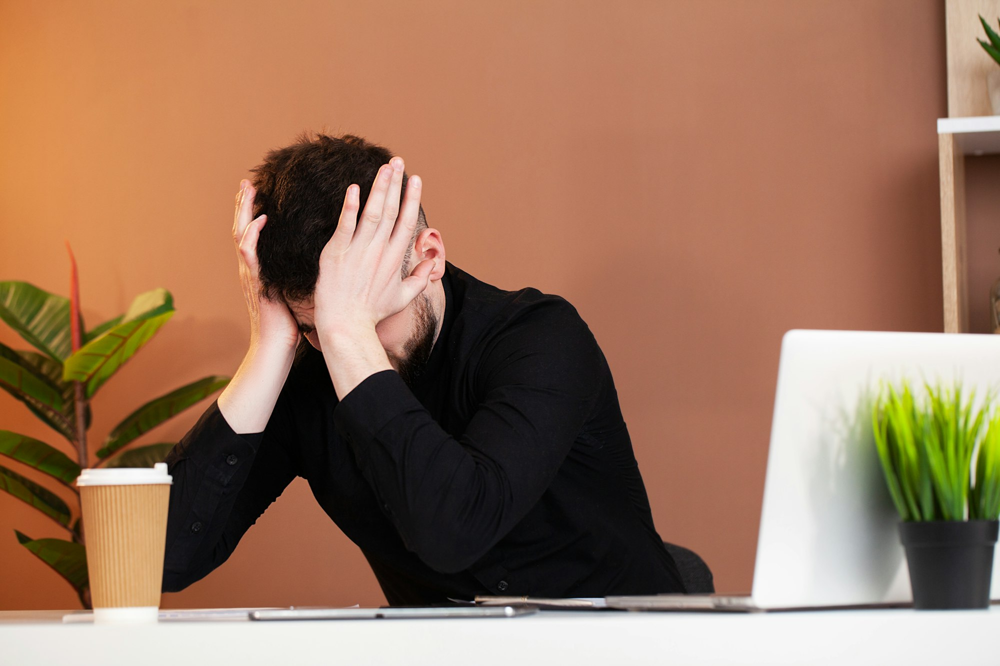 Frustrated young business man working on laptop at office