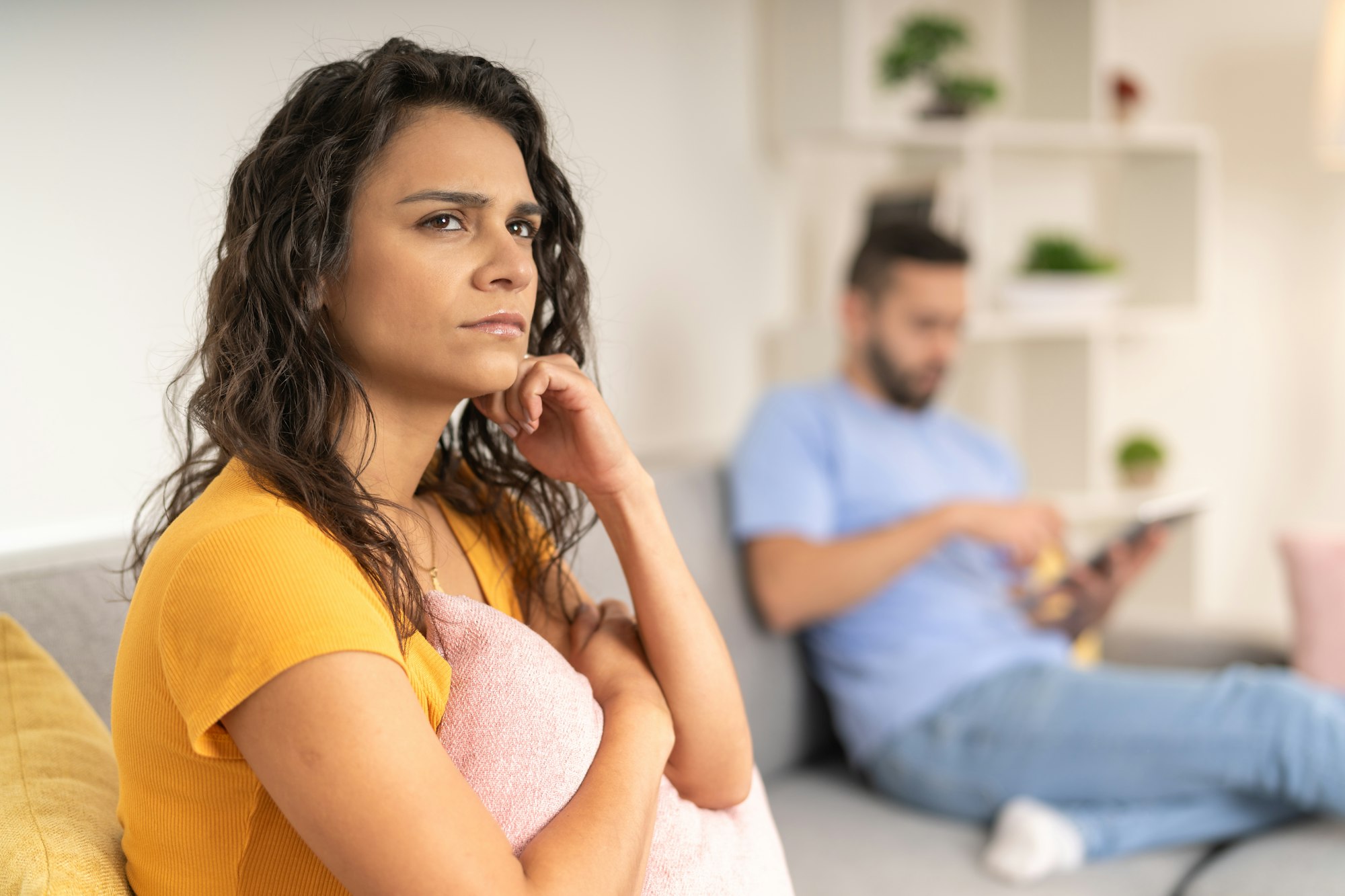 Serious woman thinking on the sofa next to her partner
