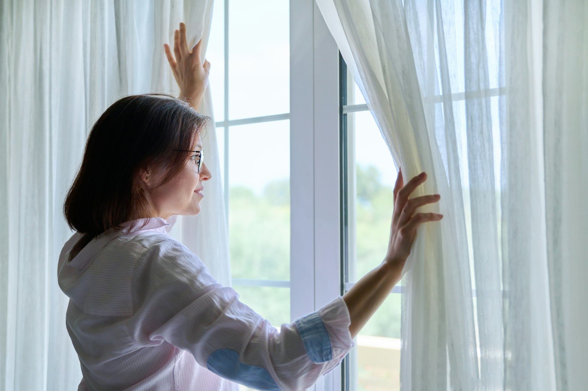 Smiling positive mature woman looking out the window